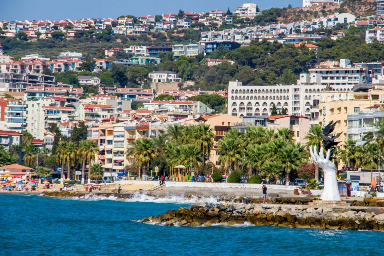 Hand statue with Kusadasi city and coastline view in the background