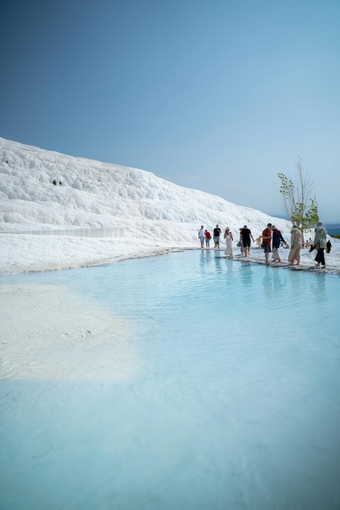 Travelers walking through thermal pools in Pamukkale
