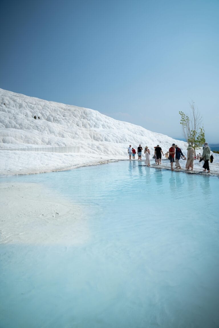 Travelers walking through thermal pools in Pamukkale