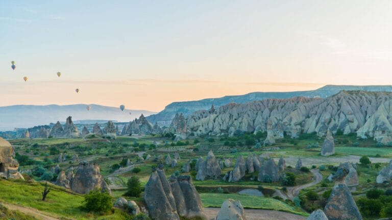 Hot air balloons flying over Cappadocia fairy chimneys in Turkey at sunrise